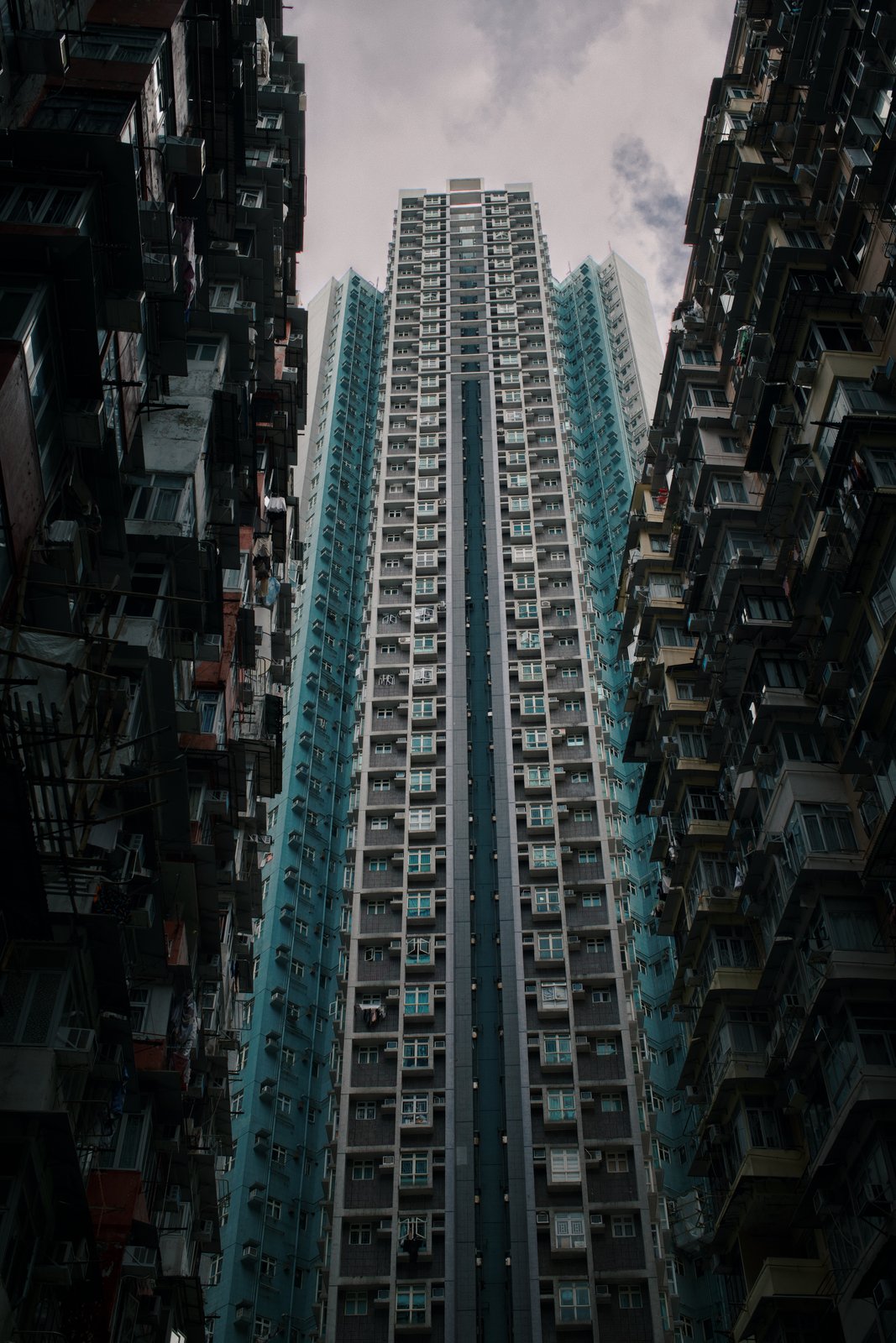 A tall teal tower framed by dense housing blocks, seen from below