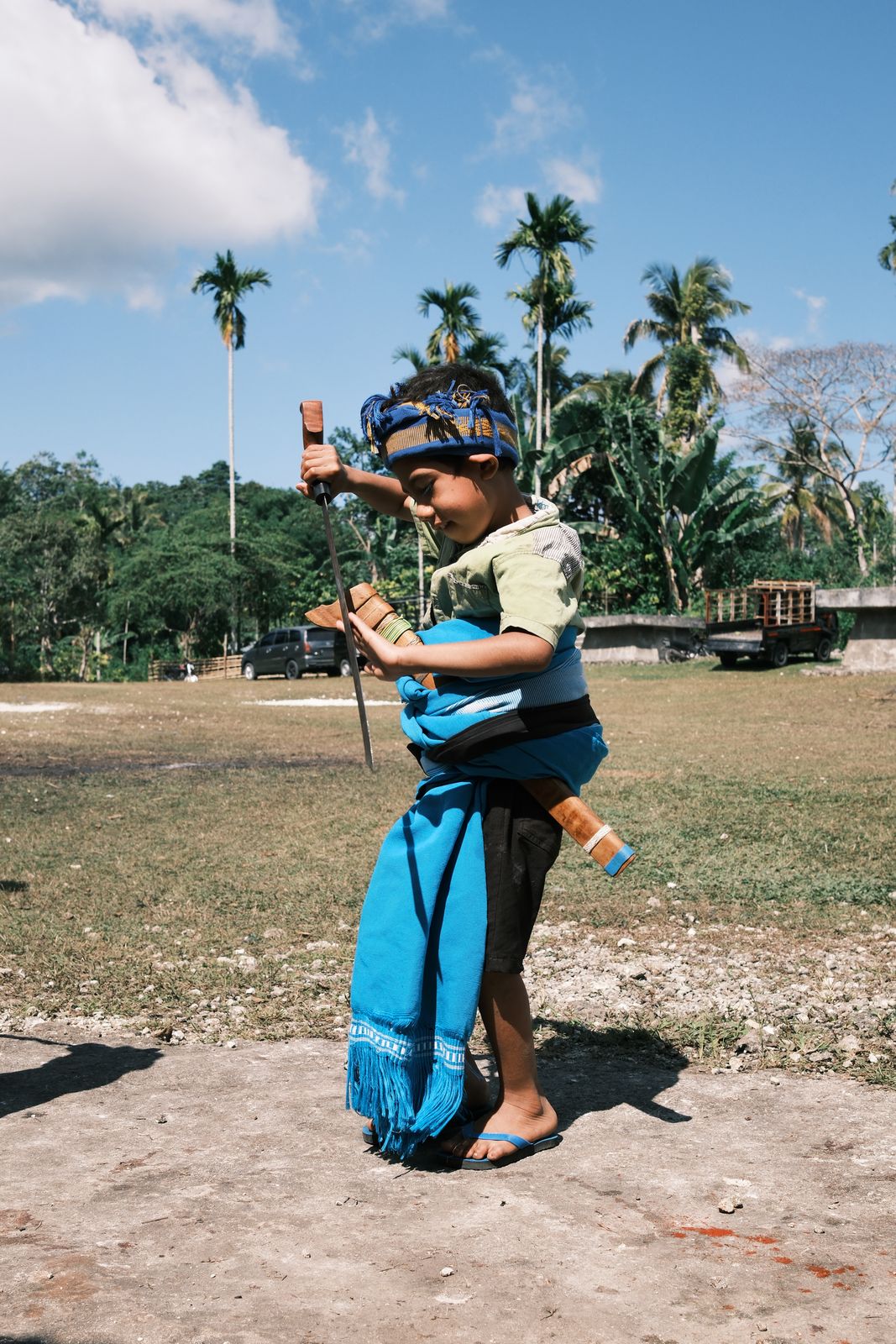 A small boy in blue ikat holding a blade