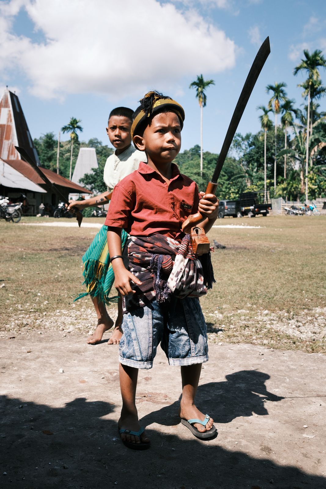 A boy walking toward the camera with a long blade