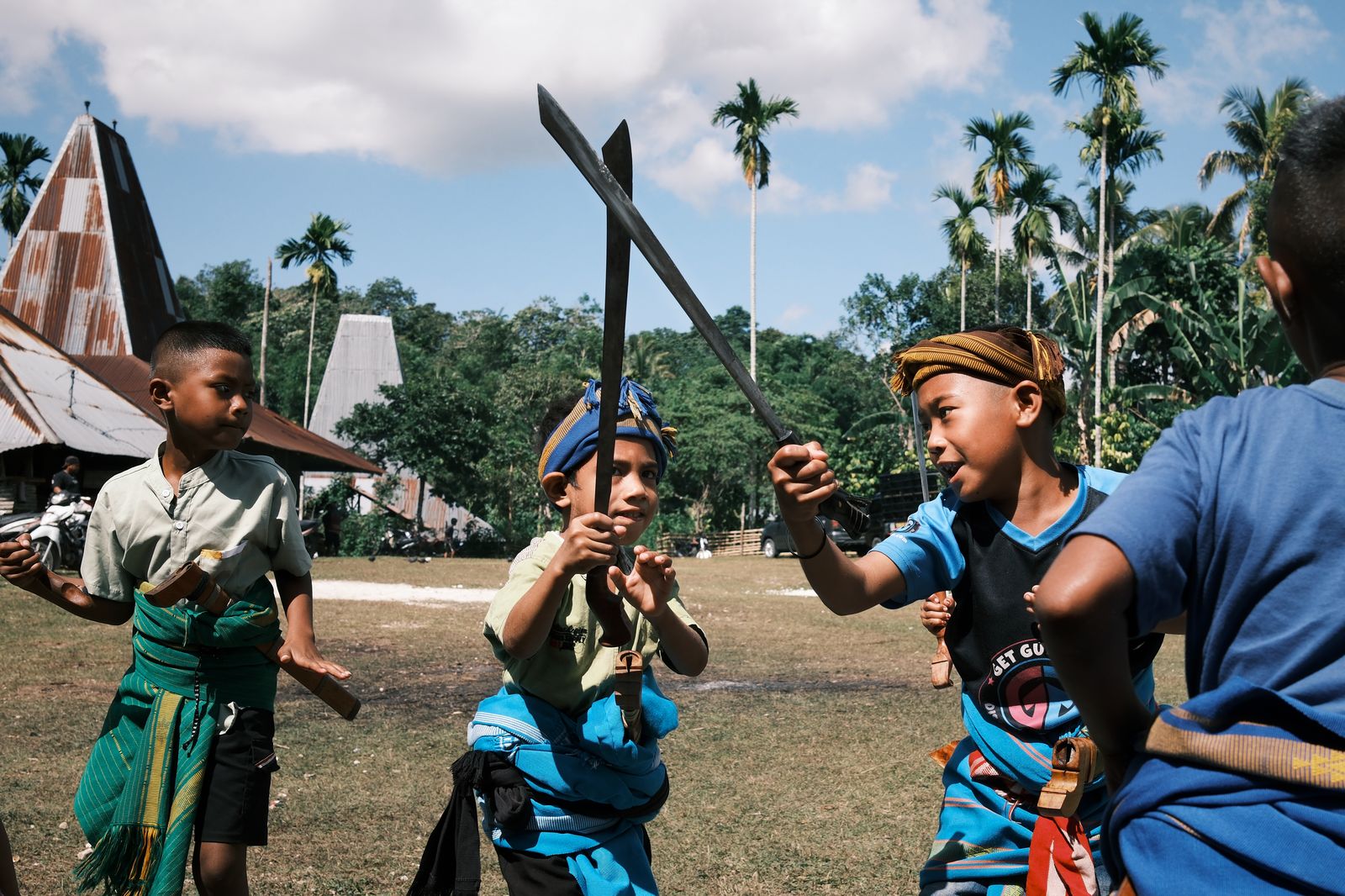 Boys in ceremonial dress holding blades aloft