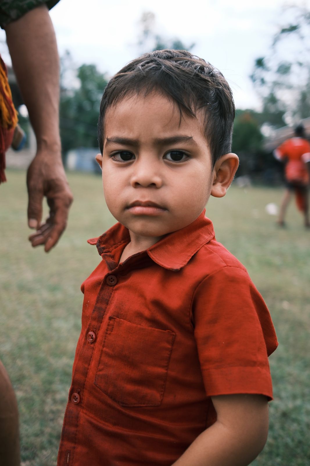 A young boy in a red shirt looking to the side