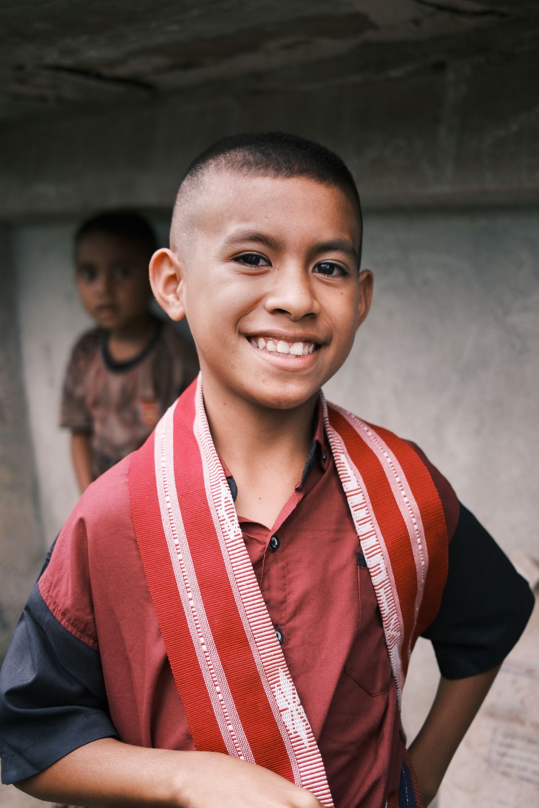A smiling boy in a red and white sash