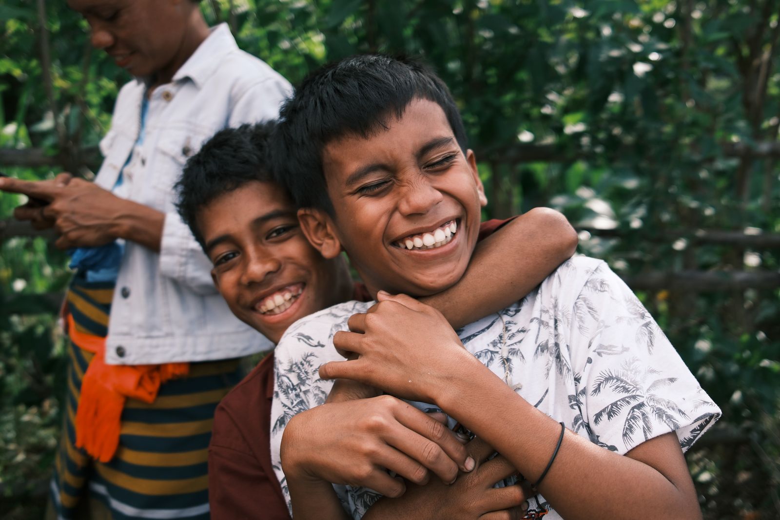 Two boys laughing, one with an arm around the other